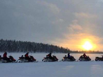 Processione di motoslitte verso il tramonto